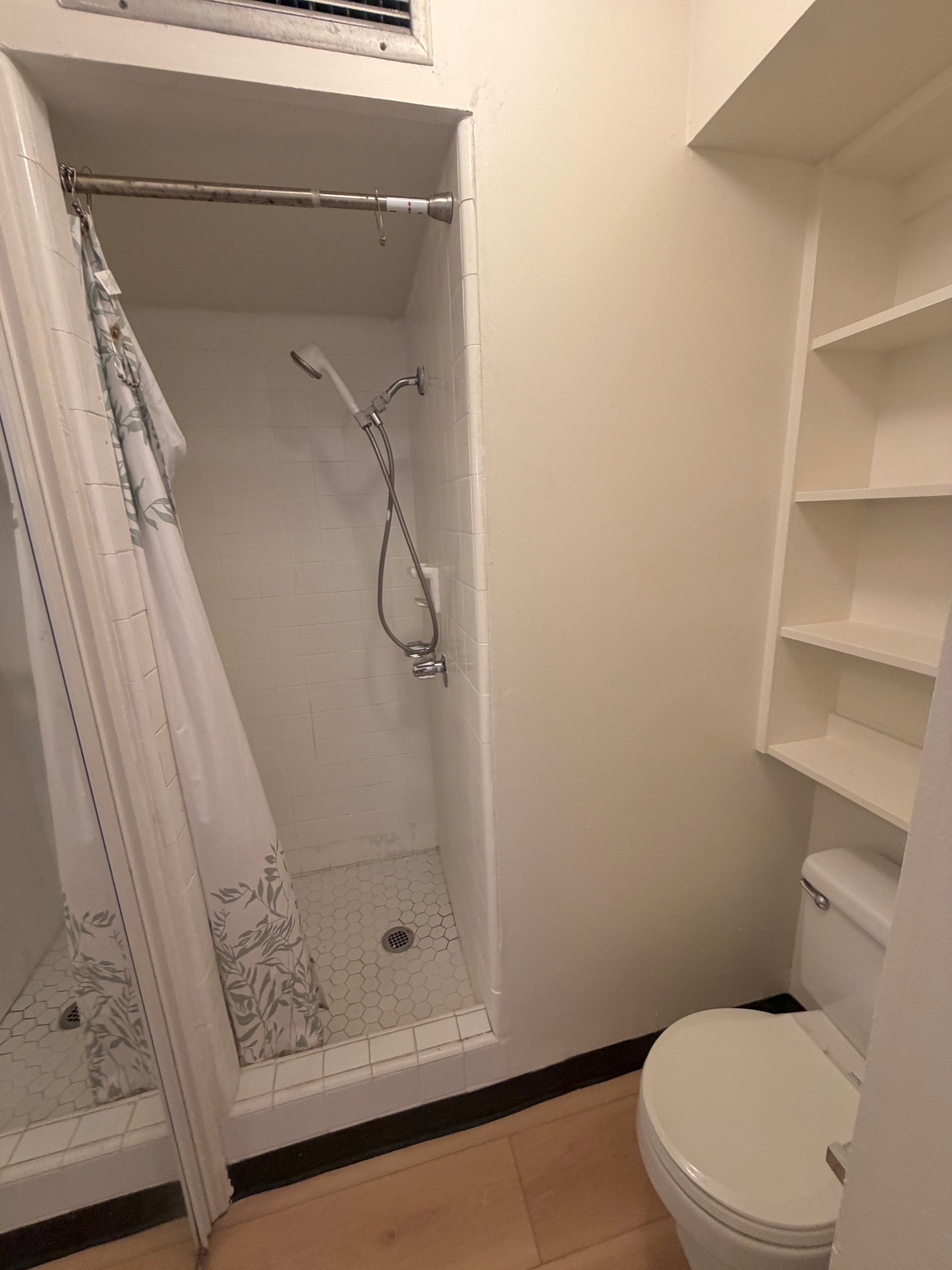 A white toilet is in a small bathroom with a walk-in shower.